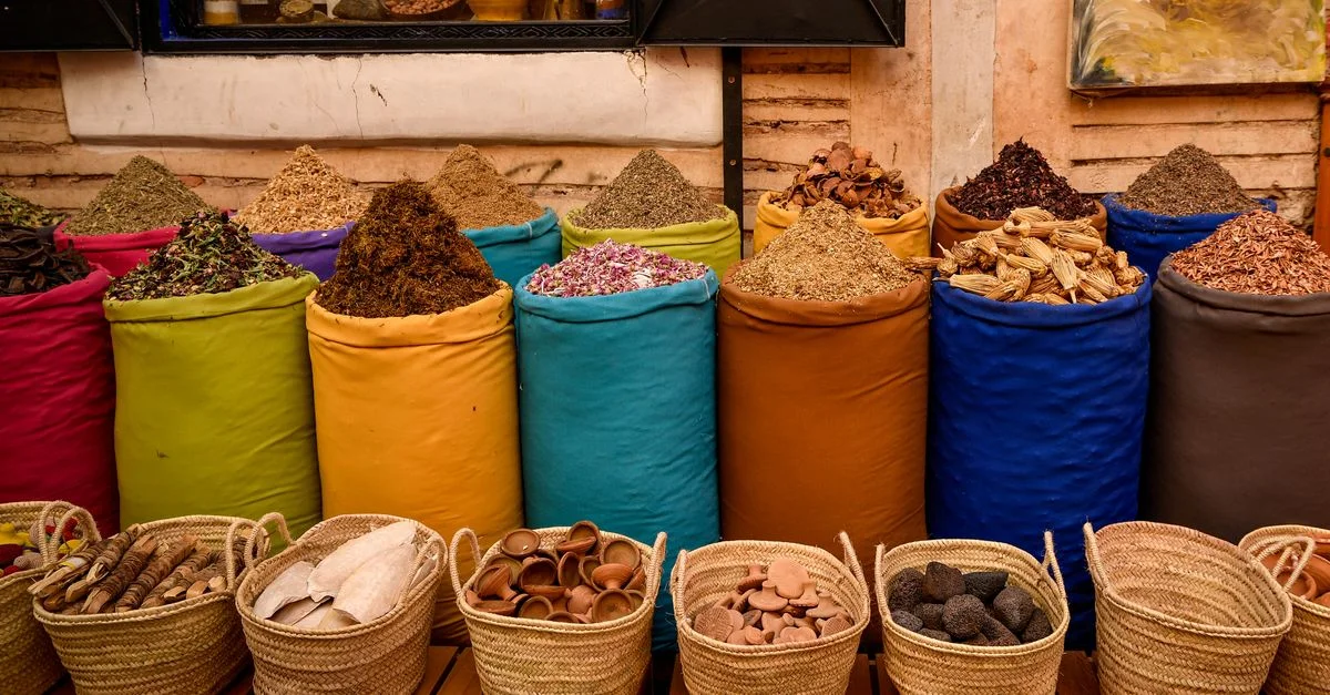 Sacs d'épices colorés dans un souk de Marrakech, illustrant la culture marocaine.
