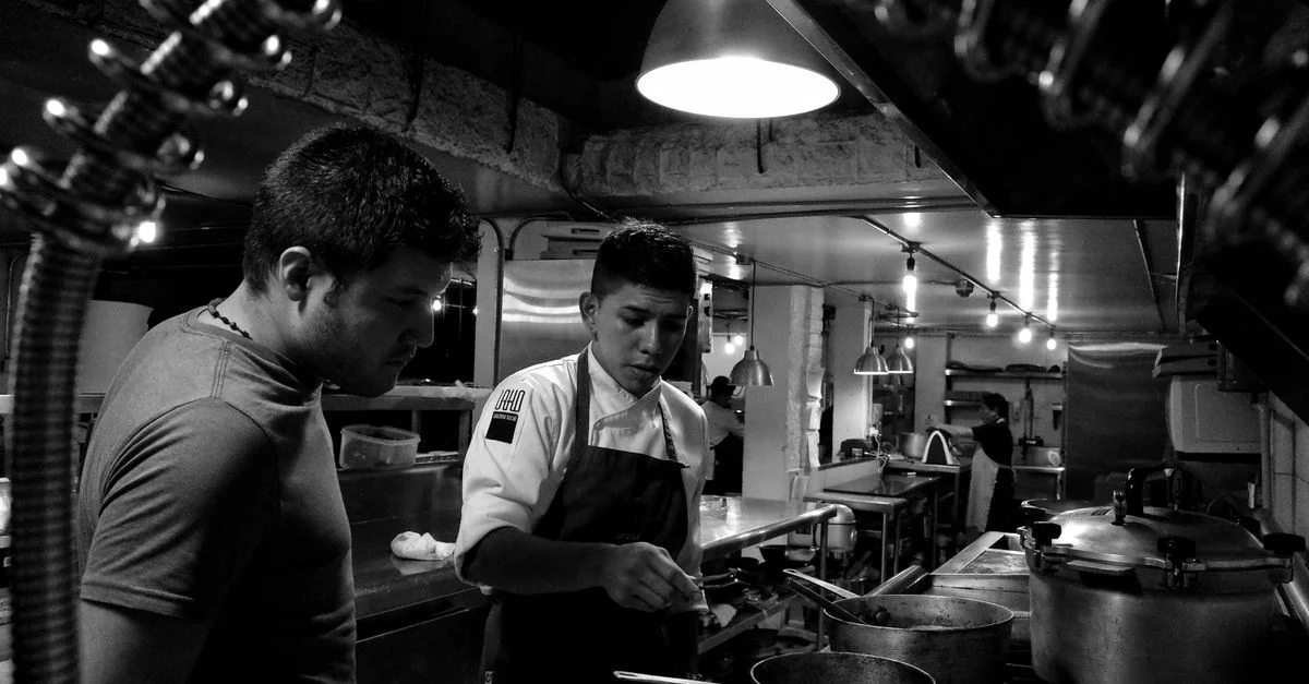 Des chefs travaillent avec attention dans la cuisine d'un restaurant, collaborant à la préparation des plats.