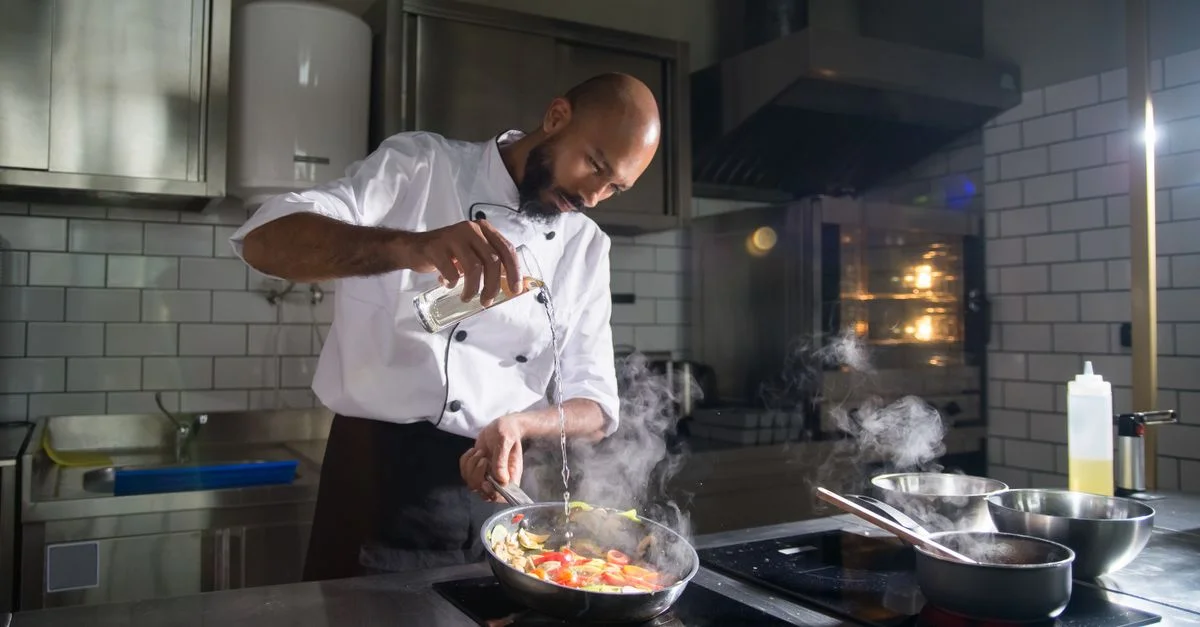 Chef cuisinant habilement dans une cuisine moderne avec des ingrédients de haute qualité.