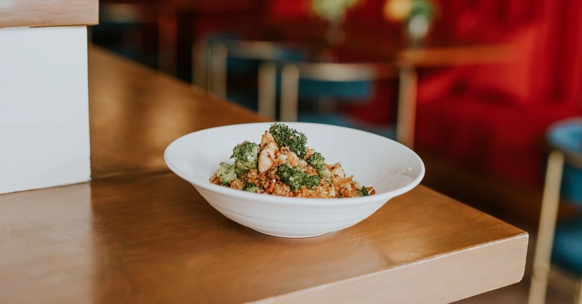 Une salade de couscous végétalienne colorée, agrémentée de brocoli et de tofu, servie dans un cadre de café moderne et intérieur.