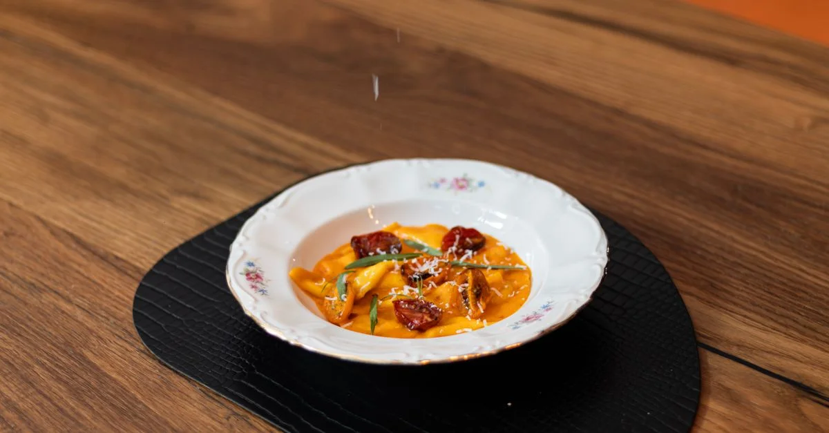 Délicieuses tagliatelles italiennes à la sauce tomate, servies dans un plat élégant, photographiées sur une table en bois rustique.